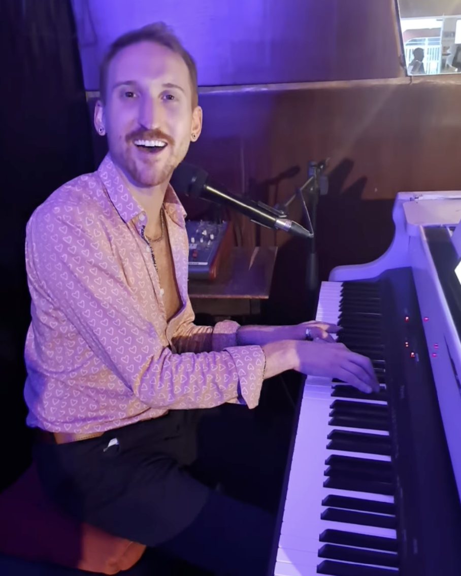 Étienne grinning mid-song at the piano, singing into a vintage microphone